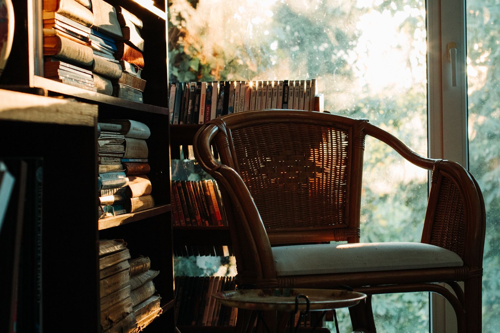 A warm, inviting reading nook with a wicker chair by a bookshelf, bathed in soft light.